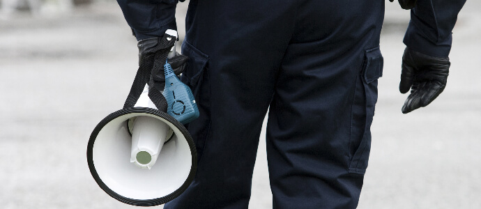 A police holding a bullhorn/megaphone with blurred background