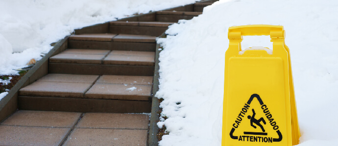 Slippery path in winter with caution sign