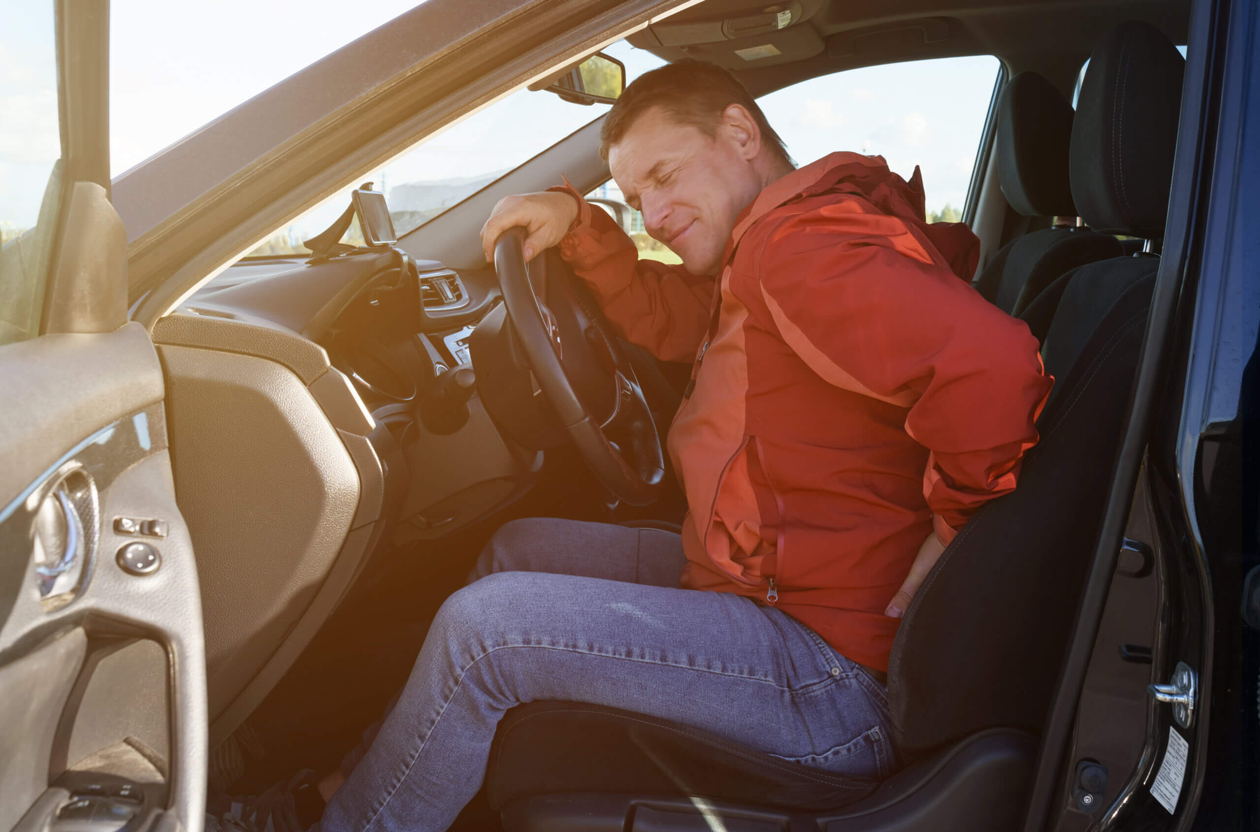 man experiencing back pain in car