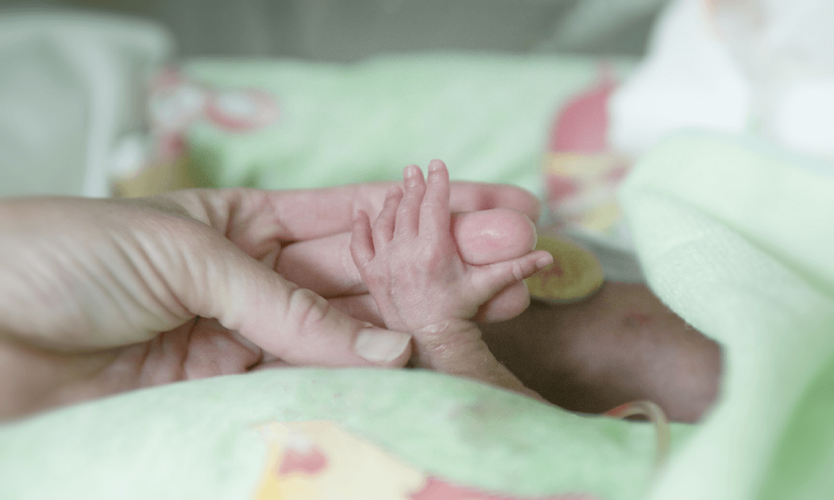 Mother holding newborn baby's hand