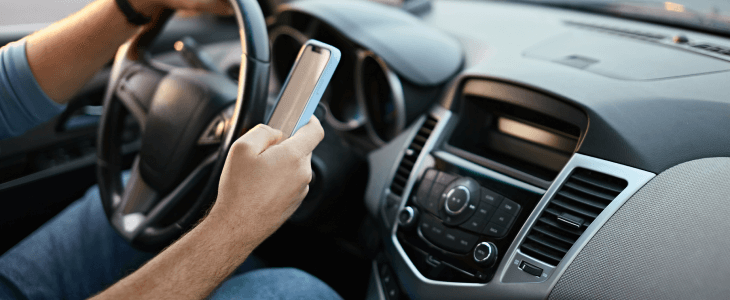 Man with cellphone in his hand while driving.