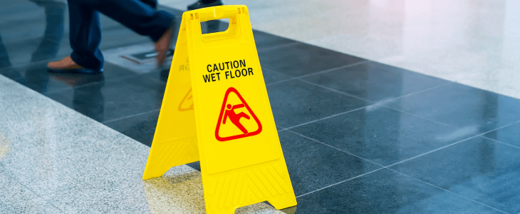 A "Caution Wet Floor" sign in the middle of a slippery walkway.