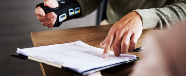 Injury, compensation and man hands with insurance documents, legal contract and paperwork. Disability, accident and people in lawyer or attorney meeting for advice, agreement or policy report closeup