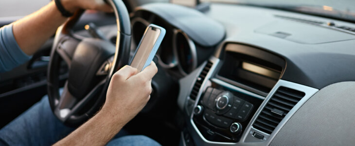 Hands of unrecognizable man driver using mobile phone while driving.