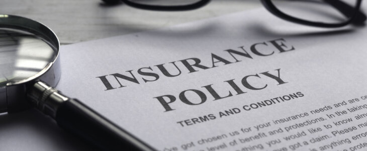 Selective focus of magnifying glass,glasses and Insurance Policy letter on a white wooden background.