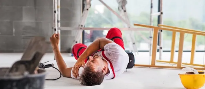 Injured construction worker lying on floor near fallen ladder