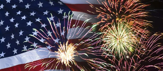 Fireworks bursting against a waving American flag