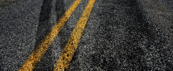 Close-up of double yellow road lines with dark skid marks